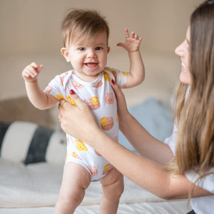 cute baby standing in the wee bean super soft organic cotton baby onesie bodysuit romper in dim sum from taste of hong kong collection