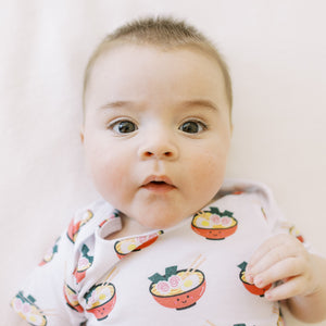 the wee bean close up of baby in organic cotton onesie in ramen noodles